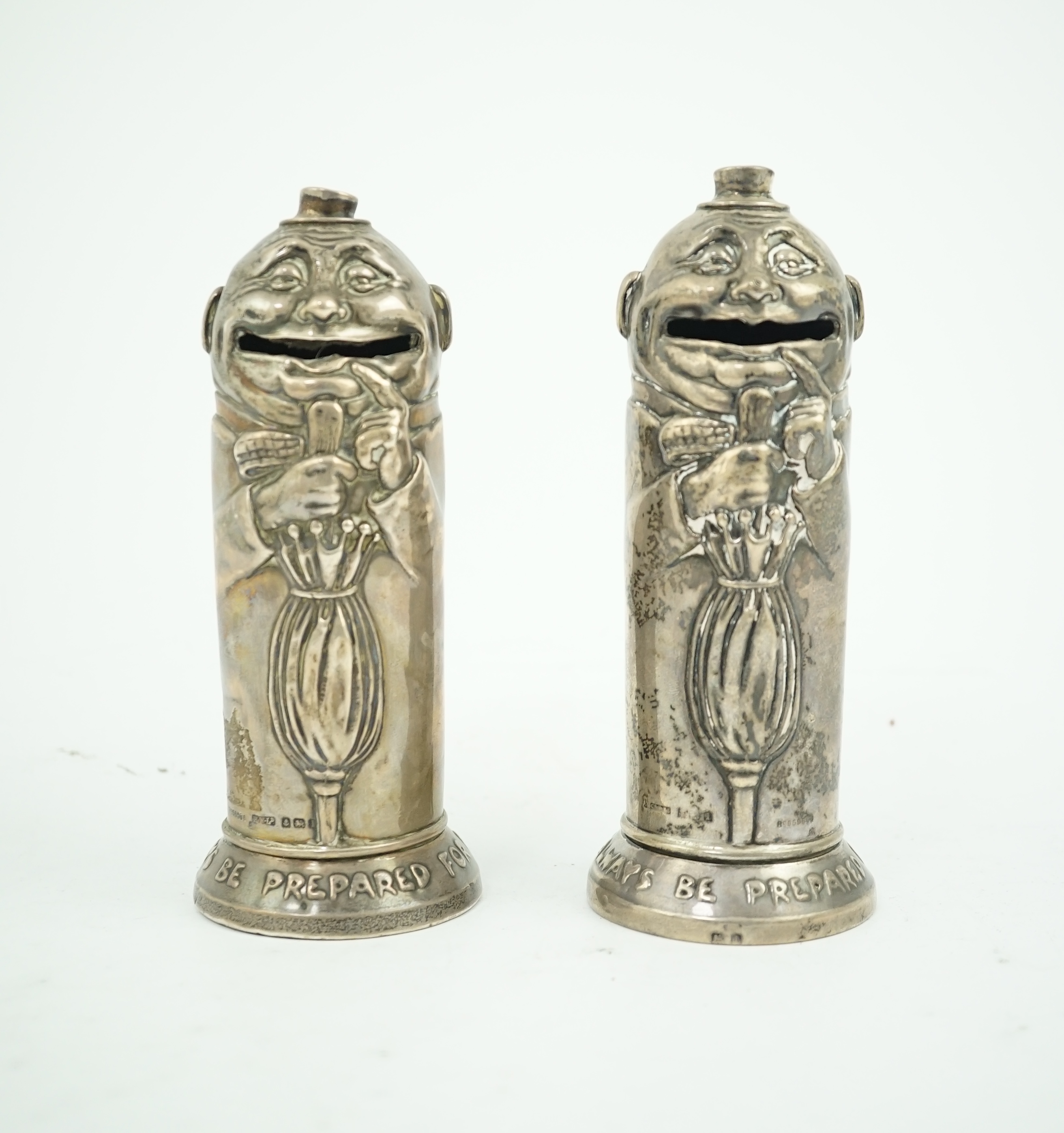 A matched pair of George V novelty silver money boxes, each cylindrical box embossed as a banker with an umbrella, the circular base inscribed 'Always be prepared for a rainy day'